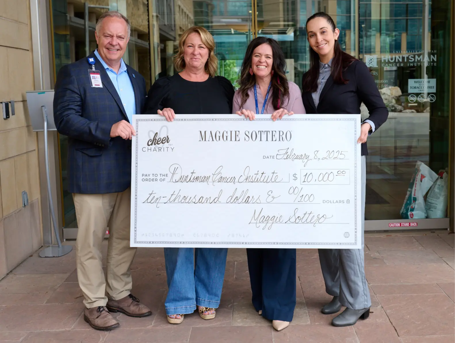 Two people holding up a large check from the Huntsman Cancer Institute.
